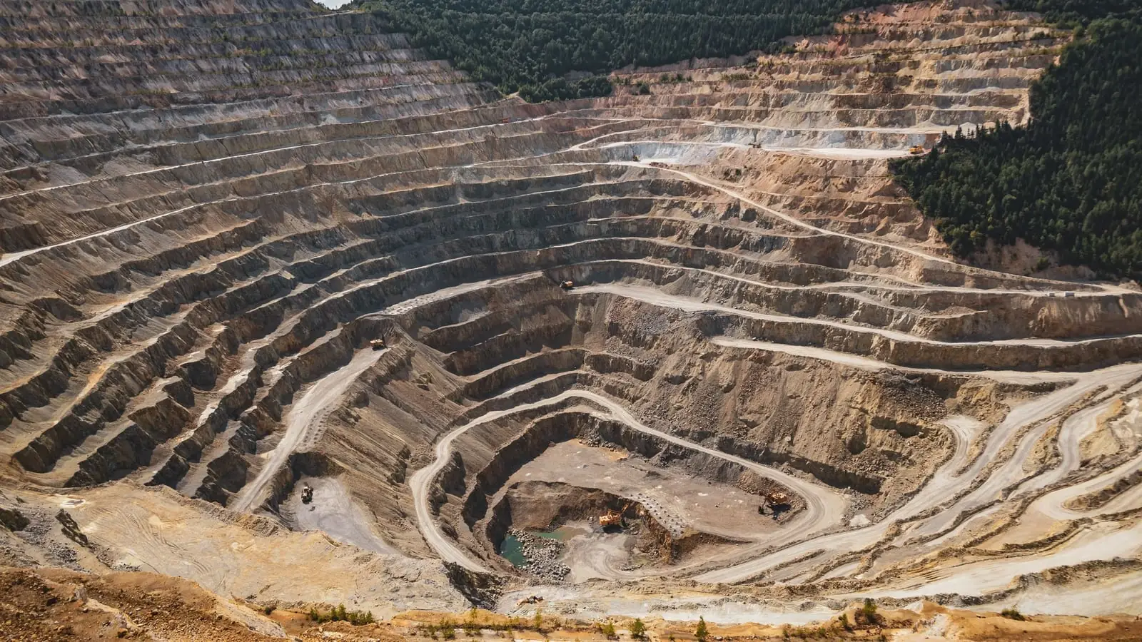 Terraced benches and haul trucks in an open-pit mine