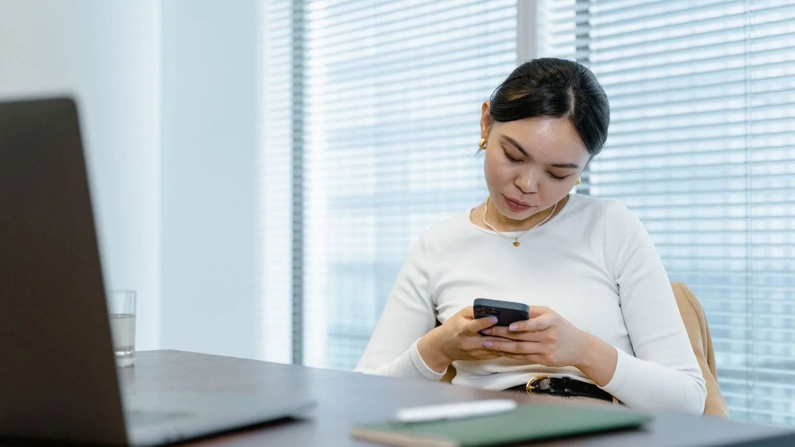 Professional reading a WhatsApp conversation on a phone at a desk
